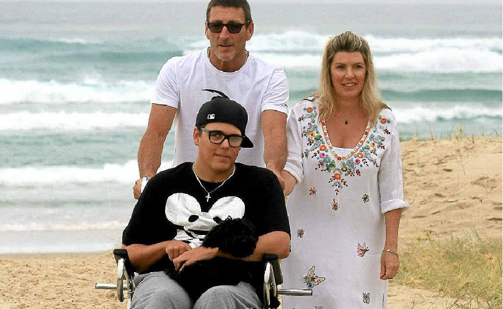 Cabarita man Sam Ford and his parents Michael and Margaret are thrilled the family can access the beach with a custom-built wheelchair funded by Tweed Shire Council and stored at the Cabarita Surf Club.